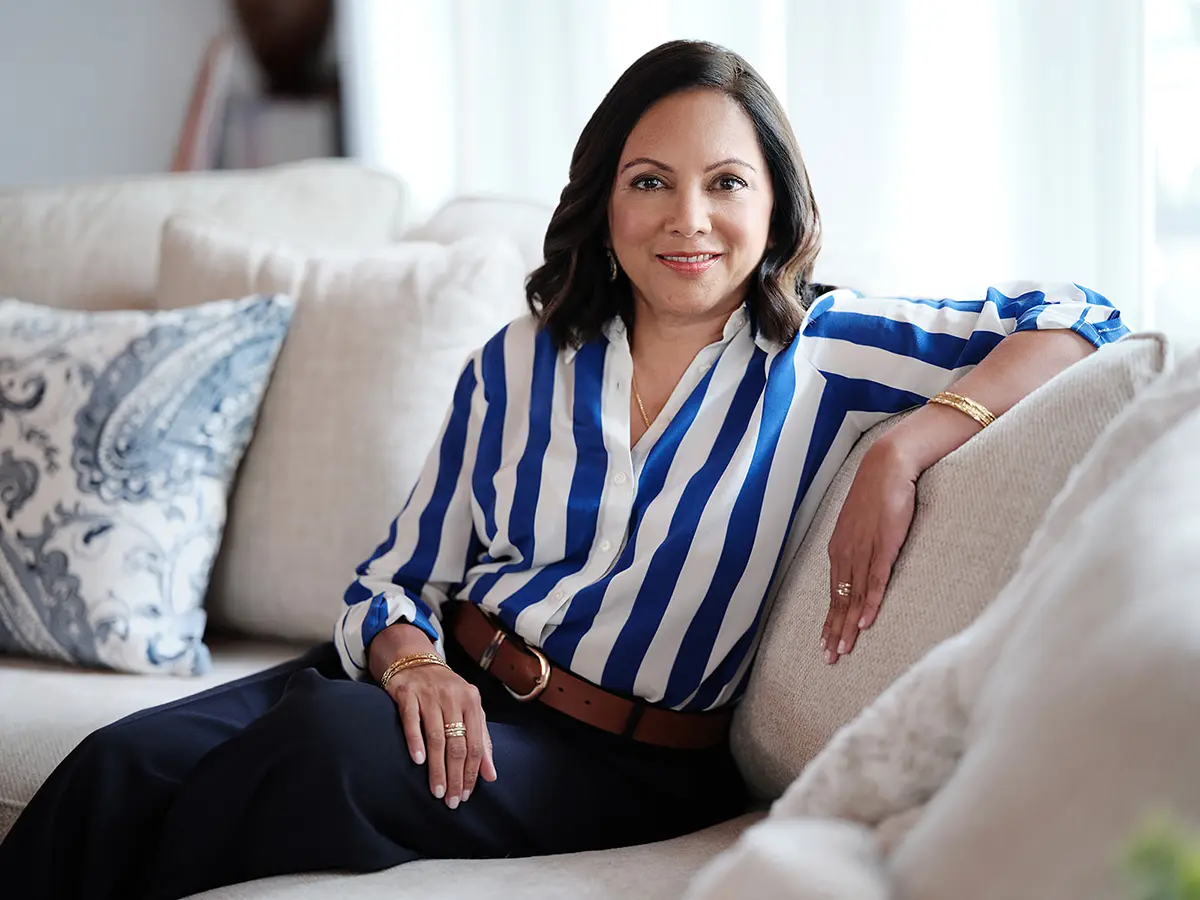 Chitra Ragavan, positive instigation executive coach, in a blue and white striped blouse, sitting on a couch